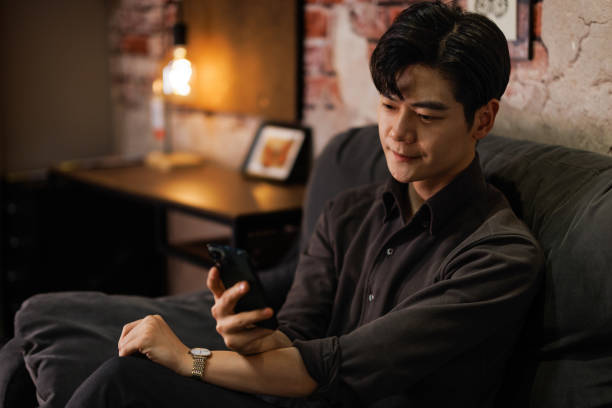 istock Young Asian men sitting on the sofa using mobile phones 1470875830