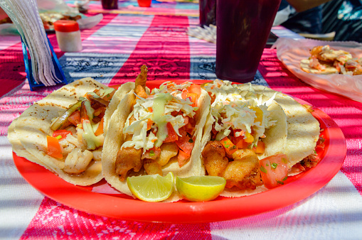 Mexican Baja fish tacos in Todos Santos with fresh sauce on colorful background. Tacos of scallop, marlin, white fish and shrimp with habanero salsa