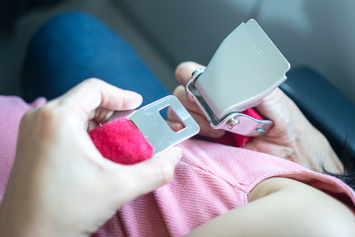 Action of a mother hand is inserting  and fastening the seatbelt for baby body during sitting in airplane. Transportation with safety action secene and safety equipment object. selective focus.