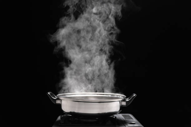 Steam over cooking pot in kitchen on dark background. stock photo