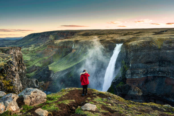 Haifoss waterfall flowing in volcanic canyon and traveler taking a picture among the Icelandic Highlands in summer stock photo