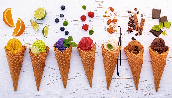 Various of ice cream flavor in cones blueberry ,lime ,pistachio ,almond ,orange ,chocolate ,vanila and coffee setup on shappy wooden background . Summer and Sweet menu concept.