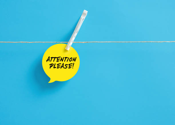 Attention please message on a speech bubble hanging on clothesline with a clothespin.