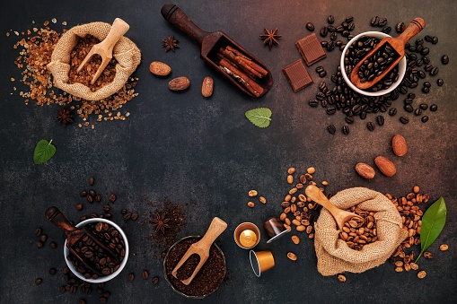 Coffee background with various of roasted coffee beans and flavourful ingredients for make tasty coffee setup on dark stone background.