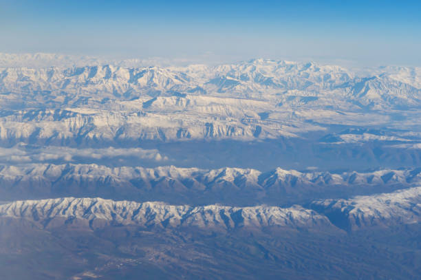 旅行と輸送のコンセプトで窓から雲の上を飛ぶ飛行機ジェットの航空写真の翼。冬の白い雪山。自然の風景の背景。 - mountain range earth sky airplane ストックフォトと画像