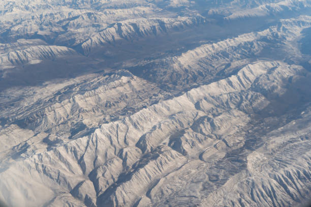 旅行と輸送のコンセプトで窓から雲の上を飛ぶ飛行機ジェットの航空写真の翼。冬の白い雪山。自然の風景の背景。 - mountain range earth sky airplane ストックフォトと画像
