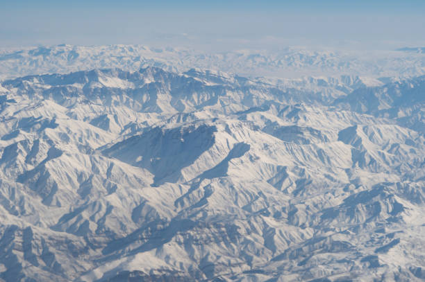 旅行と輸送のコンセプトで窓から雲の上を飛ぶ飛行機ジェットの航空写真の翼。冬の白い雪山。自然の風景の背景。 - mountain range earth sky airplane ストックフォトと画像