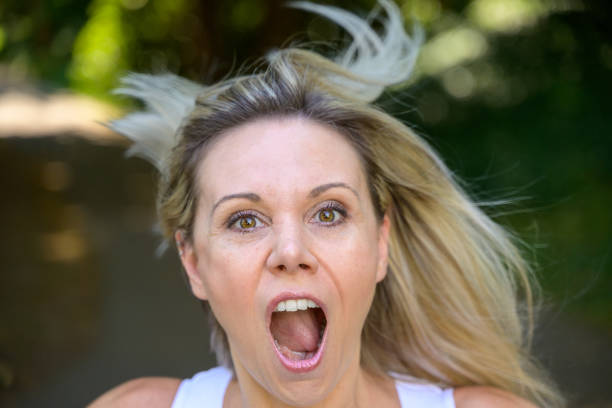 Angry middle aged woman yelling at the camera in frustration outdoors in a garden