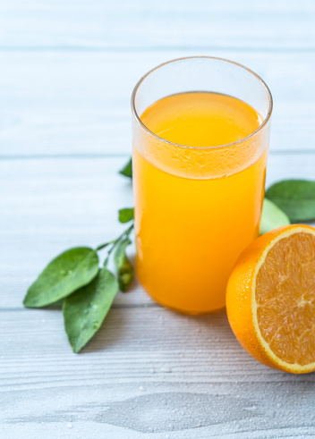 Orange juice and oranges on kitchen countertop, directly above, table top shot. Fresh fruit juice in glass bottle and drinking glass.