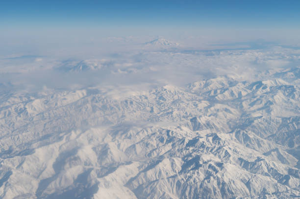 旅行と輸送のコンセプトで窓から雲の上を飛ぶ飛行機ジェットの航空写真の翼。冬の白い雪山。自然の風景の背景。 - mountain range earth sky airplane ストックフォトと画像