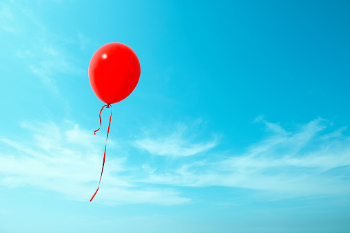 Red balloon flying in the blue sky with copy space.