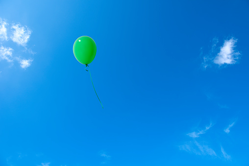 Green balloon flying in the blue sky with copy space.
