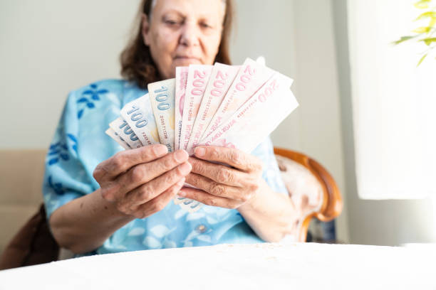 istock old women hands holding Turkish Lira banknotes 1470890213