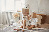 Mother and daughter in same bathrobes lying on the bed together and reading book at cozy home. Cover book mock up