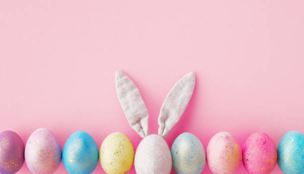 istock Easter composition with colorful Easter eggs and bunny ears on pastel pink table top view. Flat lay. 1470890383