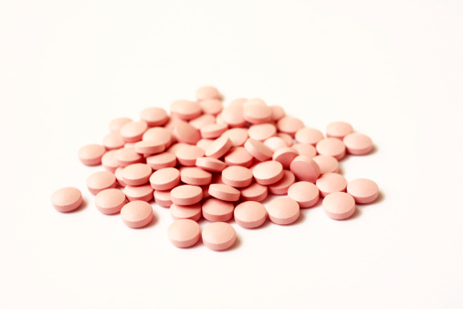 A pile of pink pills on white background.