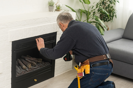 an elderly man repairs a fireplace.