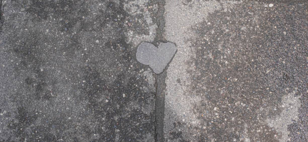 Gray concrete pavement with shape of small heart in center. Background and wallpaper texture