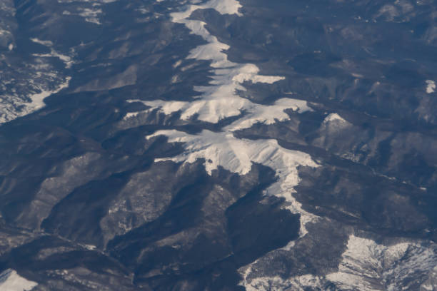 旅行と輸送のコンセプトで窓から雲の上を飛ぶ飛行機ジェットの航空写真の翼。冬の白い雪山。自然の風景の背景。 - mountain range earth sky airplane ストックフォトと画像