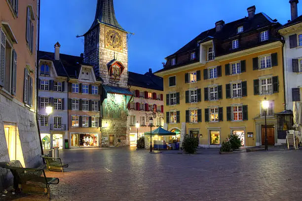 Marktplaz (marketplace) Square is the central square of Solothurn, a beautiful baroque city in Switzerland. The clock tower (Zythlogge) is the oldest surviving building (12th century with modification from 15th century) and the clock was added in 1545. Twilight HDR photo.