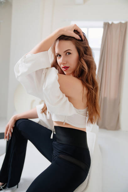 istock an attractive woman in a white top and black pants sits on a white sofa. 1470898568