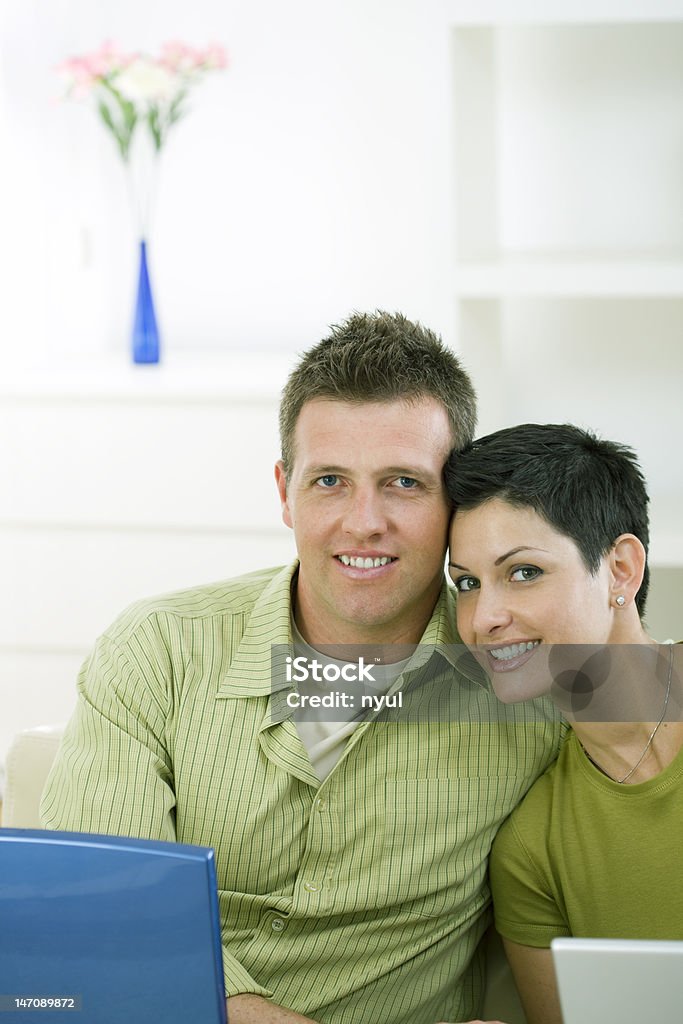 Feliz pareja joven sentada en la sala de estar - Foto de stock de 30-34 años libre de derechos