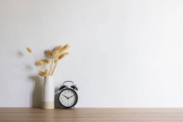 istock White flowers and clock over wooden table with natural light. 1470902650