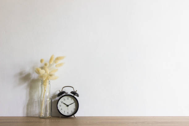 istock White flowers and clock over wooden table with natural light. 1470902651