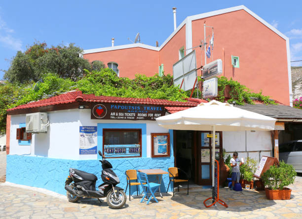 agencia de viajes con scooter y niño pequeño que limpia frente al edificio en kastellorizo, grecia - greek islands table window sun fotografías e imágenes de stock