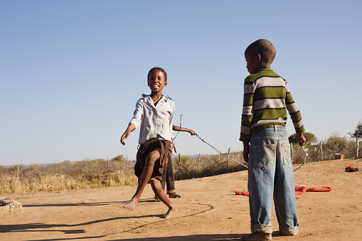 african children jumping rope in the sand, Mmankodi village Botswana