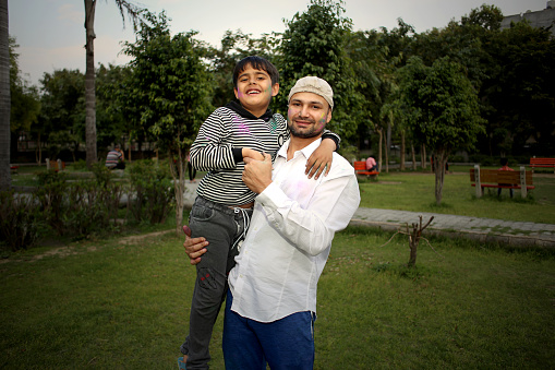 Elementary age boy with his uncle celebrating Holi festival in the park, Delhi, India.