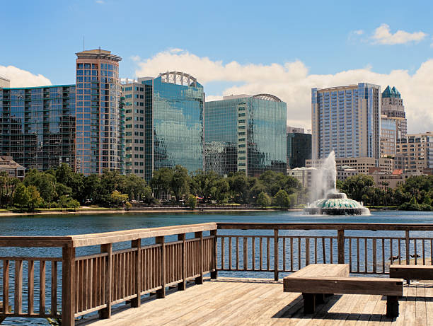 Sunny day view of Orlando's skyline with a lake and fountain Lake Eola and Orlando skyline with fountain. lake eola stock pictures, royalty-free photos & images