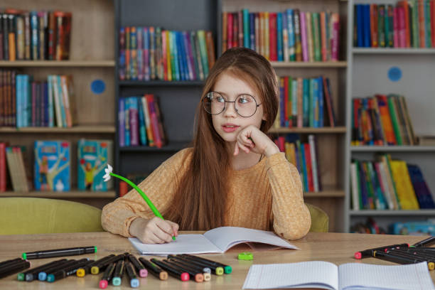 istock Pupil learning in school. Girl writes in copybook and does homework while sitting in library. 1470913340