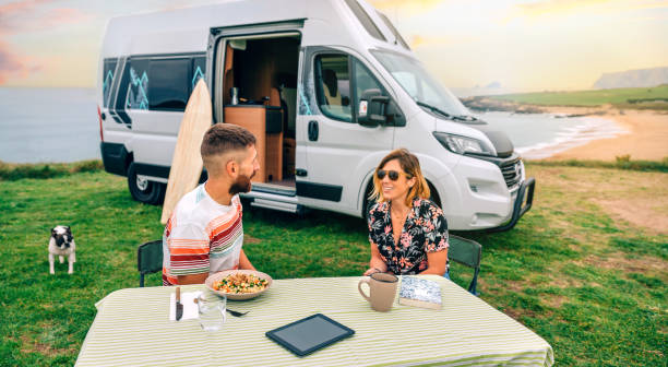 istock Couple sitting outdoors with camper van and beach on background 1470914909