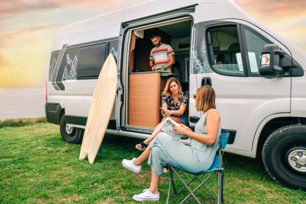 istock Two women talking in front of camper van while young man cooks 1470914911