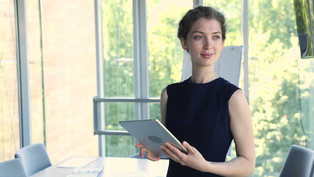 Young businesswoman working on digital tablet standing at workplace