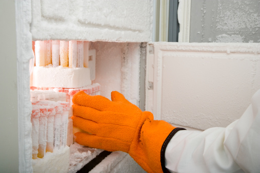 Cropped image of a researcher's arm retrieving medical samples from a freezer. Horizontal shot.