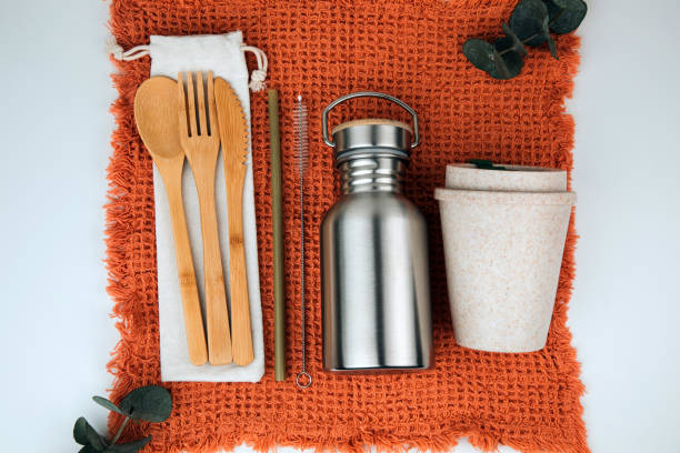 istock Set of devices for cold and hot drinks. A tin bottle for water and a folding mug, reusable straws, wooden cutlery on orange towel 1470920679