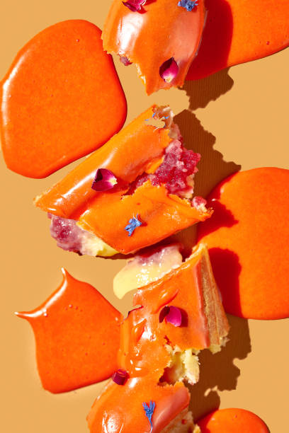 istock Art with an eclair. Broken eclair in puddles of icing on an orange background. Conceptual monochrome food poster 1470921892