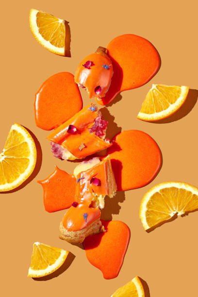 istock Art with an eclair. Broken eclair in puddles of icing on an orange background. Conceptual monochrome food poster 1470921957