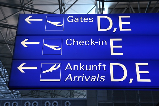 Generic airport signage in Frankfurt Airport. Illuminated gates, check-in and arrivals sign (in English and German language).