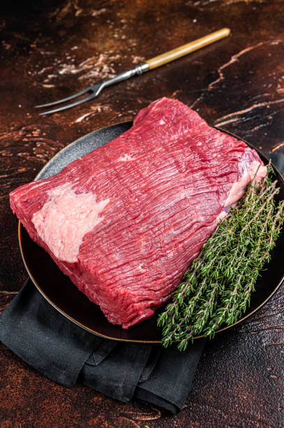 istock Fresh beef brisket, raw meat with herbs. Dark background. Top view 1470924599