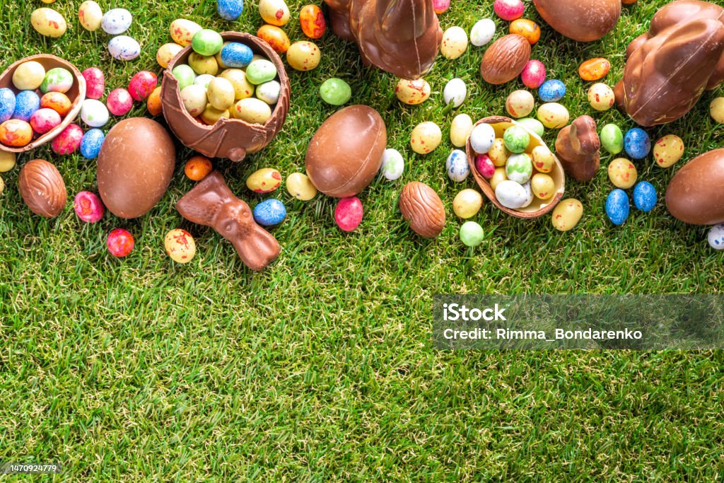 Easter egg hunting background Easter egg hunting background. Various candy and chocolate Easter eggs, bunny and rabbits with basket for eggs on green grass park or garden background Easter Stock Photo