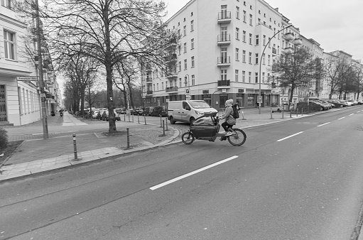 Black and white photo of young woman cycling on empty street in Berlin