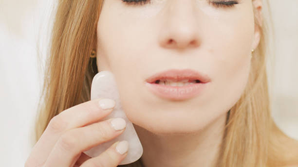 istock A red-haired woman is massaging, stroking her face with a shea stone. 1470925338