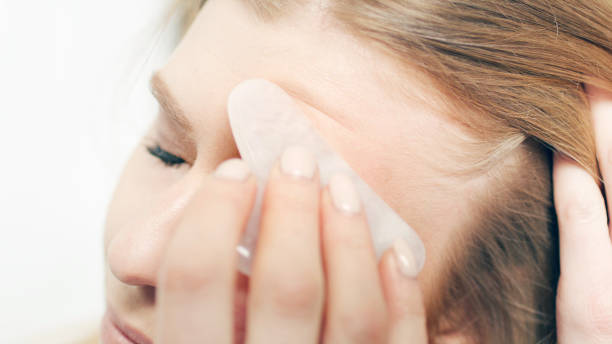 istock A red-haired woman is massaging, stroking her face with a shea stone. 1470925409