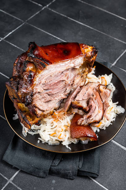 istock Roast Pork Ham Hock, knuckle with Sauerkraut on a plate. Black background. Top view 1470927363