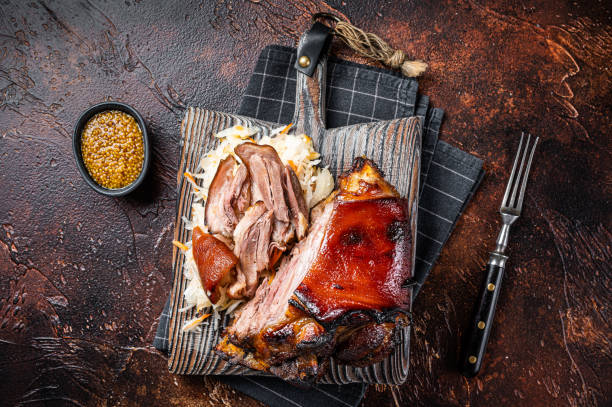 schweinshaxe pieczona szynka wieprzowa hock, golonka z kiszoną kapustą podana na drewnianej desce. ciemne tło. widok z góry - ham baked roast pork holiday zdjęcia i obrazy z banku zdjęć