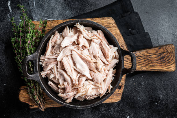 istock Sliced Pieces of chicken meat in a skillet, pulled chicken. Black background. Top view 1470928250