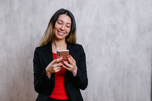 Portrait of a beautiful young businesswoman texting using smart phone indoors.